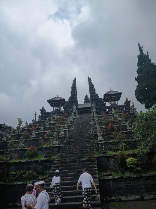 Des visiteurs gravissent les grands escaliers en pierre menant aux portes intérieures du complexe de temples hindous de Pura Besakih à Bali.