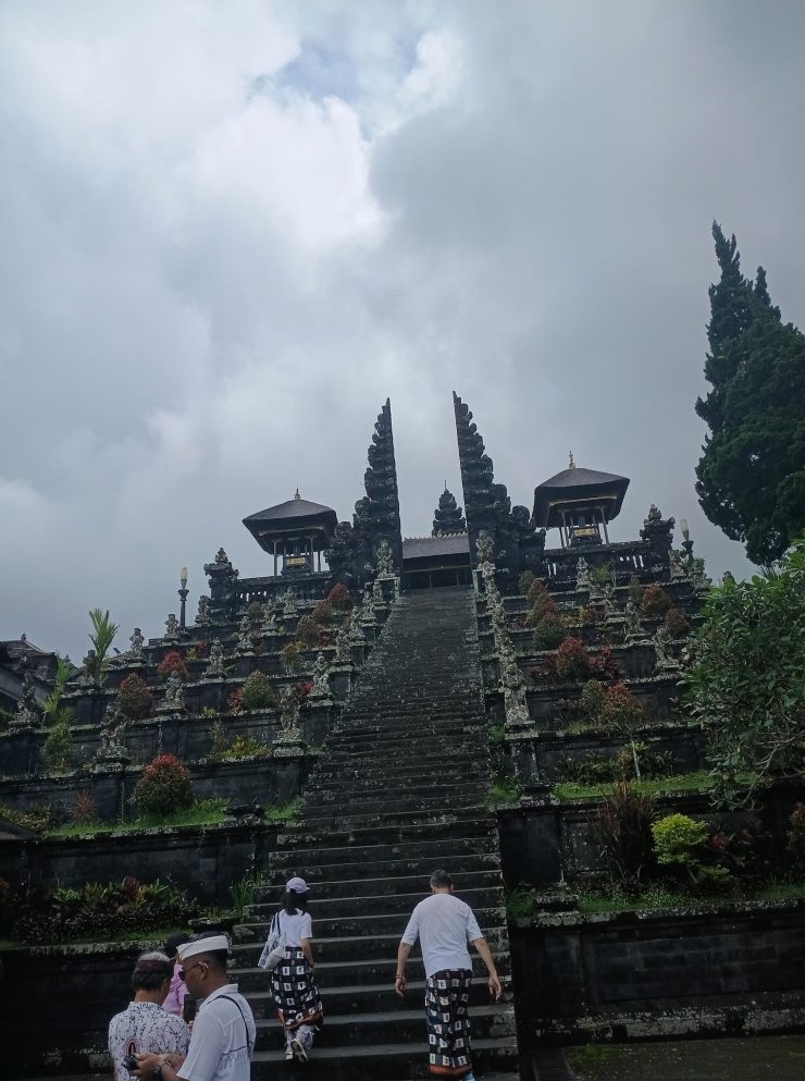 Des visiteurs gravissent les grands escaliers en pierre menant aux portes intérieures du complexe de temples hindous de Pura Besakih à Bali.